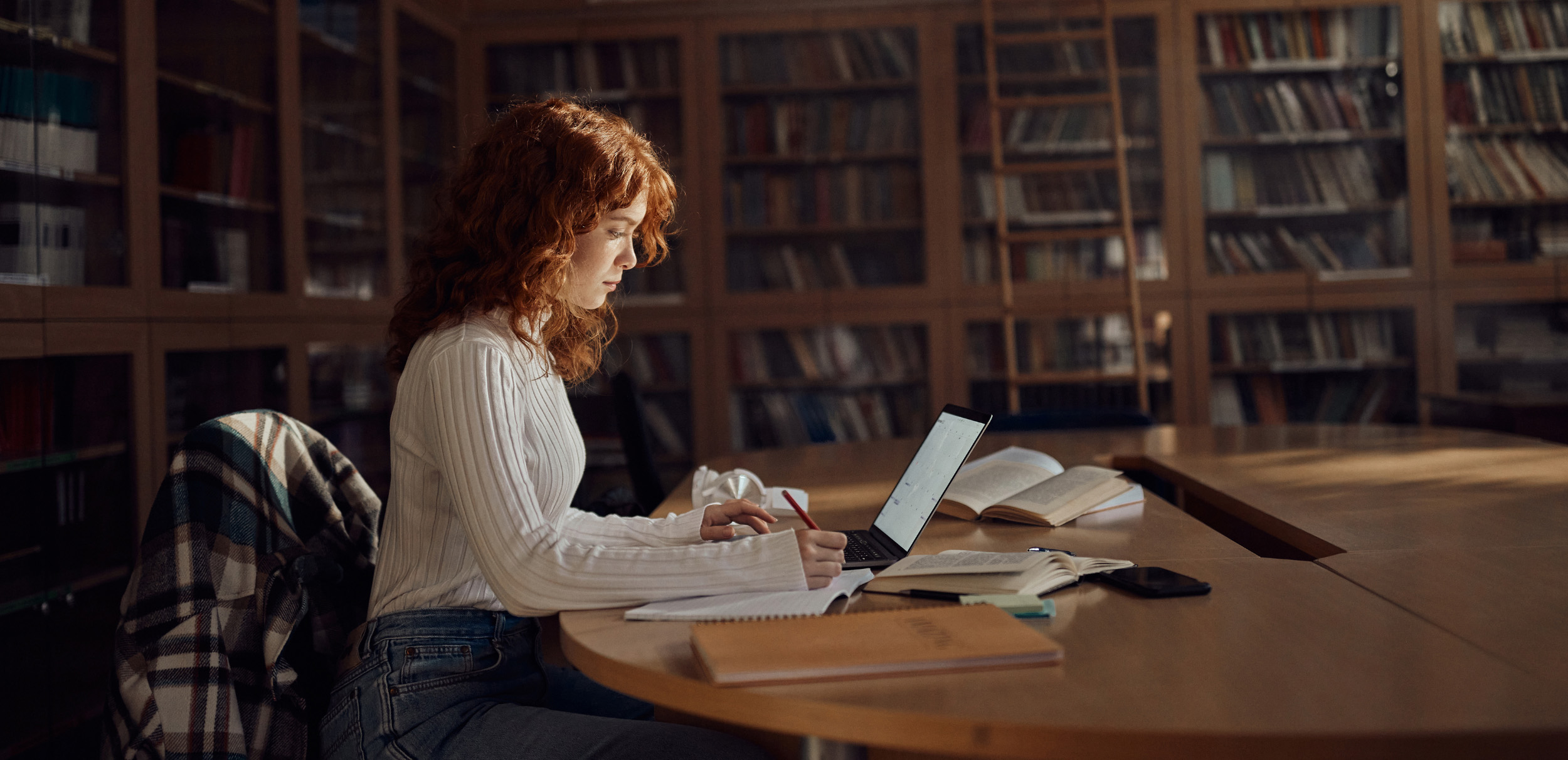 Estudiante en una biblioteca representando el modelo educativo híbrido de Estonia que combina libros tradicionales con aprendizaje digital.