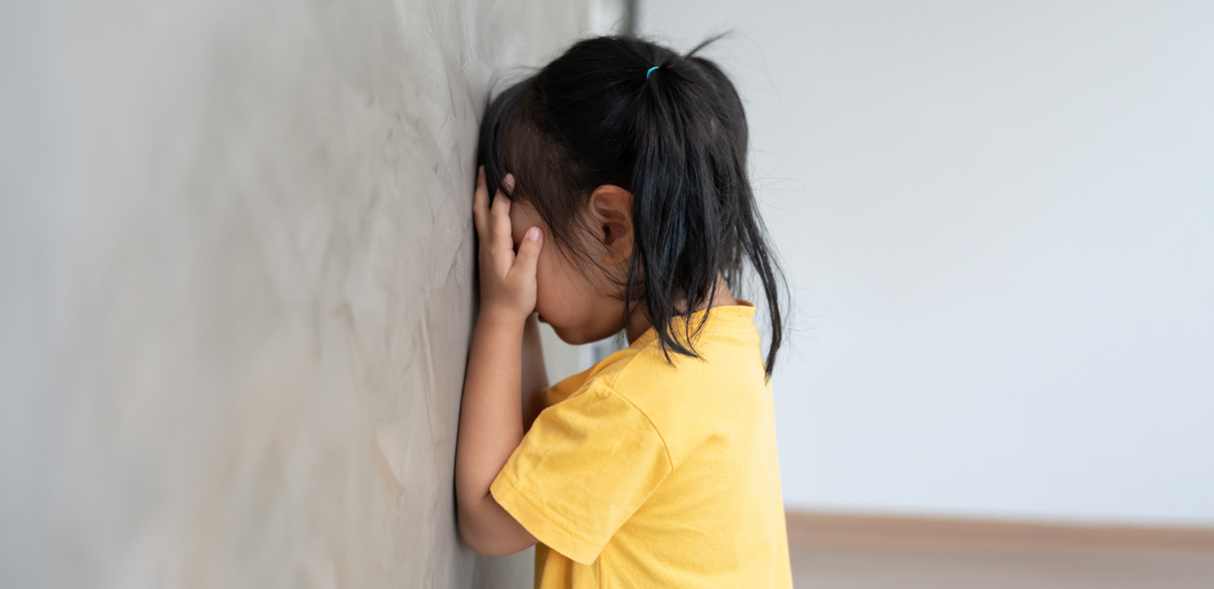 Niña tapándose la cara frente a la pared mostrando frustración o bloqueo emocional en el aula.