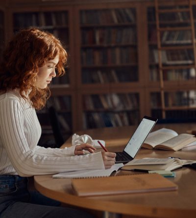 Estudiante en una biblioteca representando el modelo educativo híbrido de Estonia que combina libros tradicionales con aprendizaje digital.