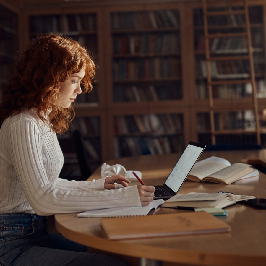 Estudiante en una biblioteca representando el modelo educativo híbrido de Estonia que combina libros tradicionales con aprendizaje digital.